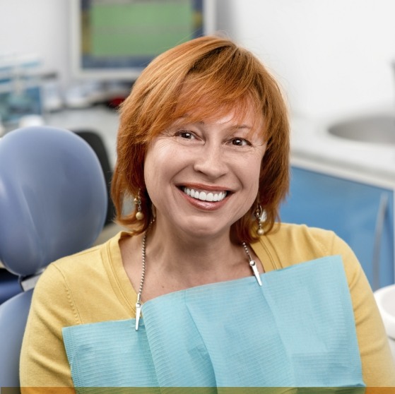 Woman with red hair smiling in dental chair