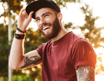 Young man in baseball cap grinning outdoors