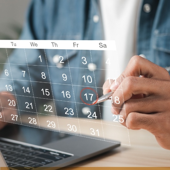 Person circling date on calendar of dental appointment