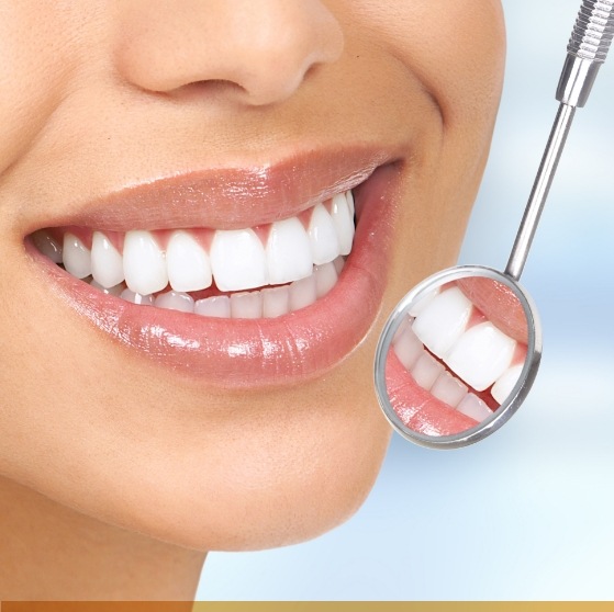 Close up of dental mirror reflecting a smile with white teeth