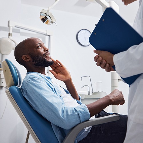 Patient smiling at dentist holding clipboard