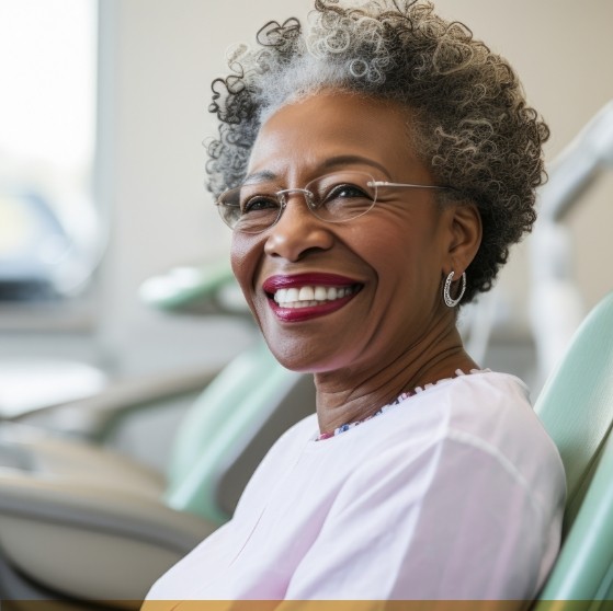 Smiling woman sitting in treatment chair at dental office in Stone Mountain