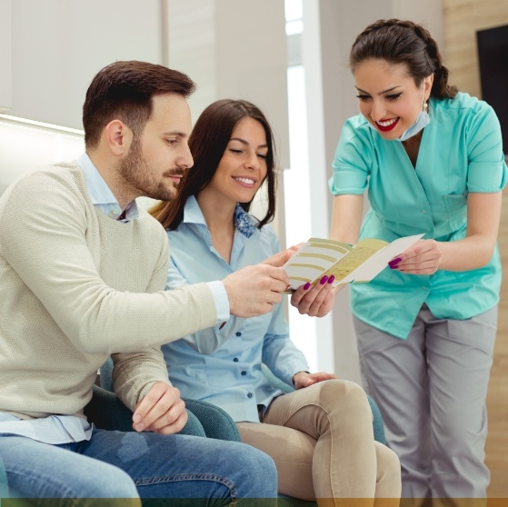 Dental team member showing a pamphlet to two patients