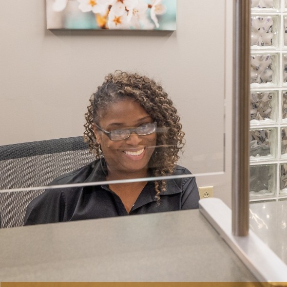 Smiling dental office receptionist sitting at front desk