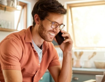 Young man with glasses smiling while talking on the phone