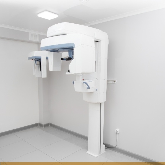 C T cone beam scanner standing against white wall of dental office