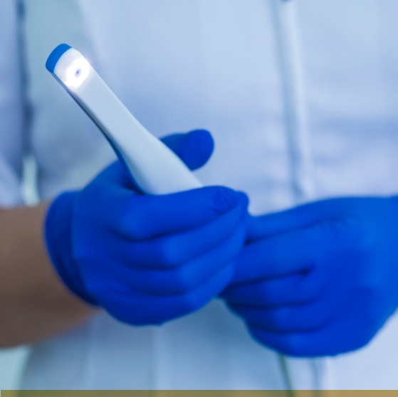 Two gloved hands holding a thin white intraoral camera