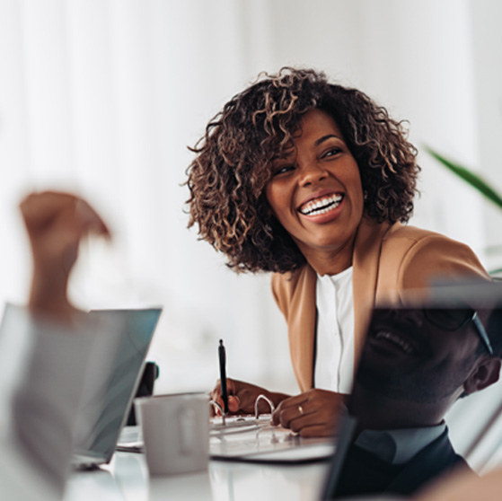 Woman smiling while taking notes during meeting