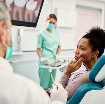 Patient with toothache looking at dentist in treatment chair