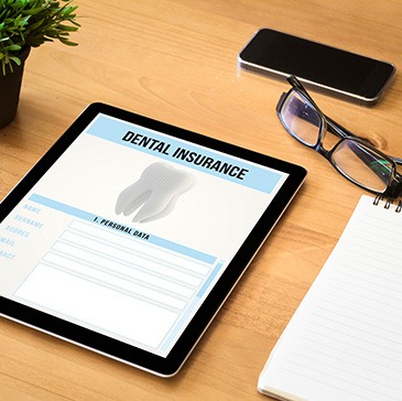 Dental insurance form on tablet next to office supplies