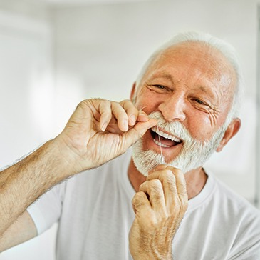 Man smiling while flossing his teeth