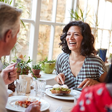 Woman smiling while eating with friends at restaurant