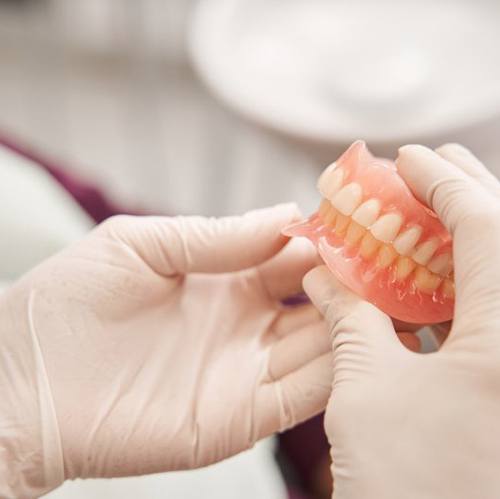 Dentist carefully holding a denture