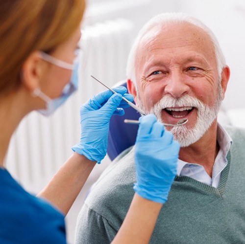 Man smiling as dentist examines his teeth