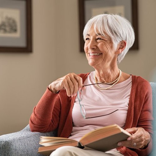Woman smiling while reading a book in an armchair