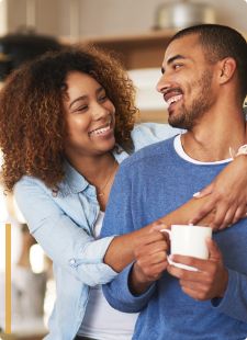 Woman hugging a man holding a white coffee mug