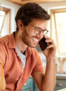 Man with glasses smiling while talking on phone
