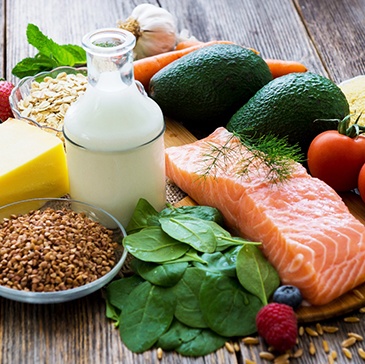 Variety of healthy foods including protein, veggies, and fruits on a wooden table