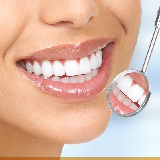 Close up of dental mirror reflecting a smile with white teeth