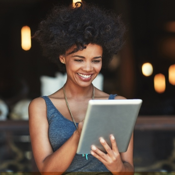 Woman looking at tablet for dentist reviews in Stone Mountain