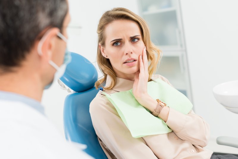 Patient holding their cheek because they need a tooth extraction