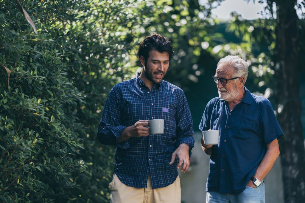 Two men outside talking carrying white mugs